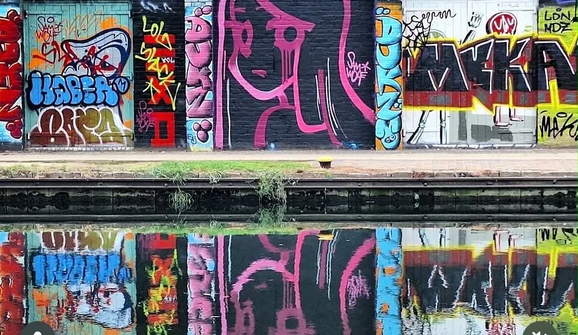 Graffiti lettering and pink portrait reflected in water