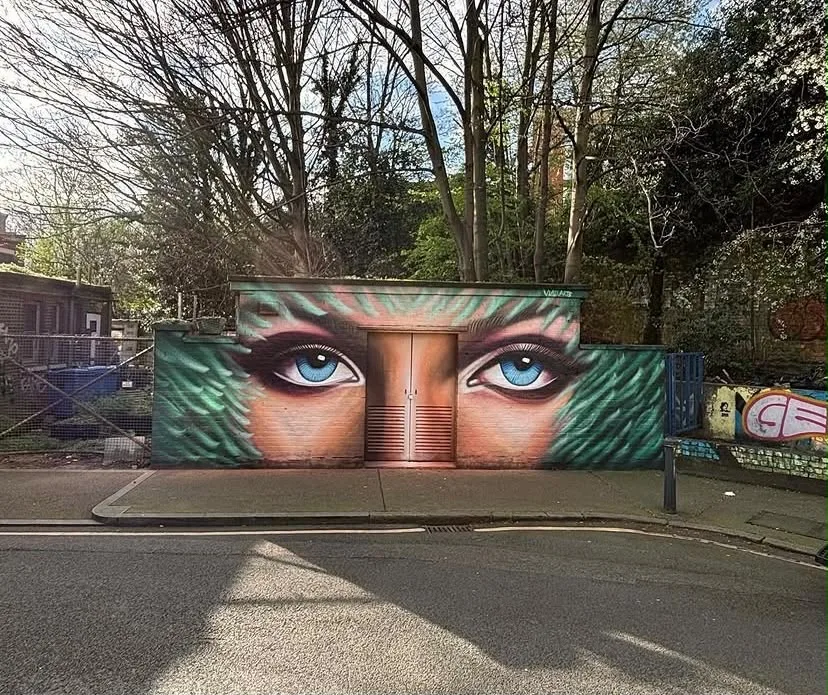 Blue eyes and foliage painted across a streetside building