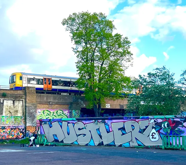 Large graffiti artwork on an outdoor wall beside a railway