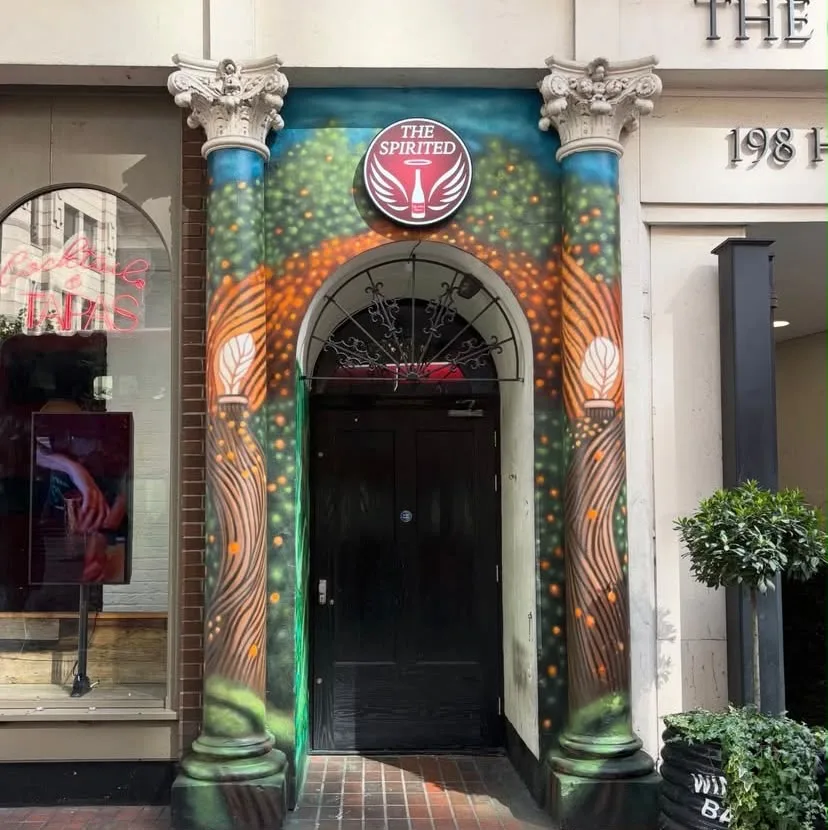 The Spirited entrance framed by painted blue columns and foliage